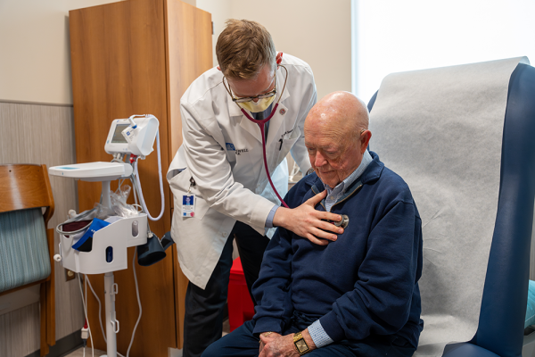 Dr. Patrick Seastedt uses a stethoscopic on with an older patient in an exam room